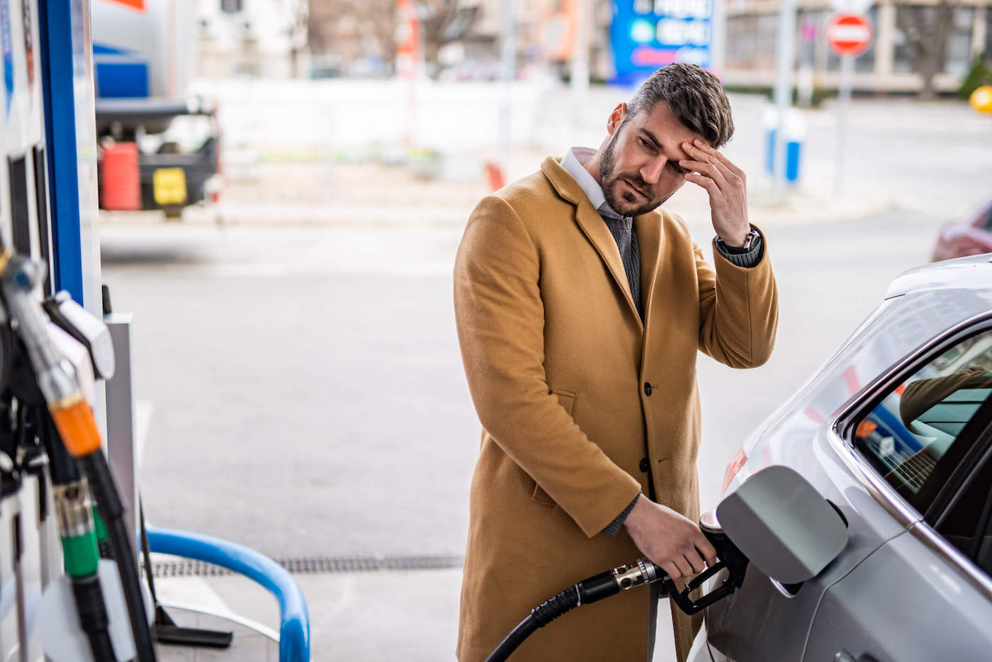 Man Has Hands On His Head While Pumping Gas In Car